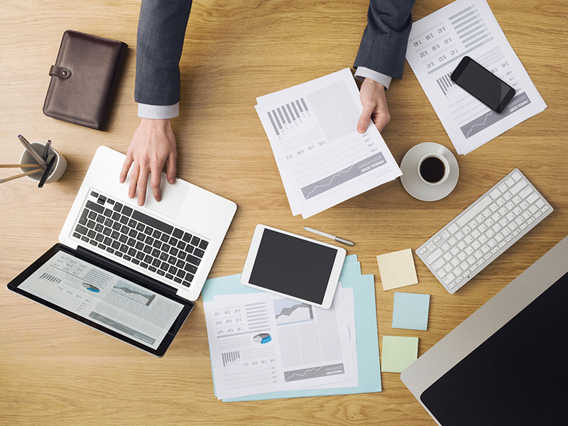 Bureau de travail avec ordinateur, tablette et paperasse.