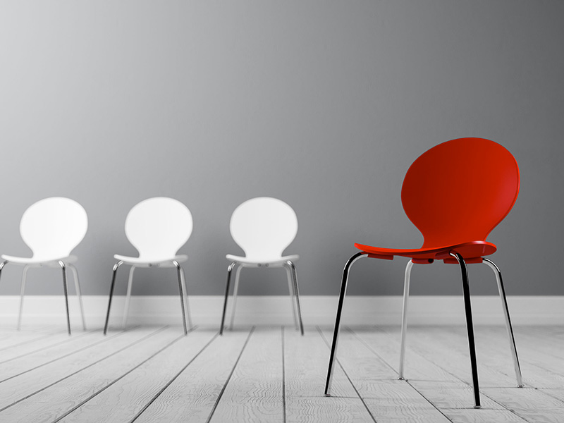 Trois chaises blanches et une chaise rouge.