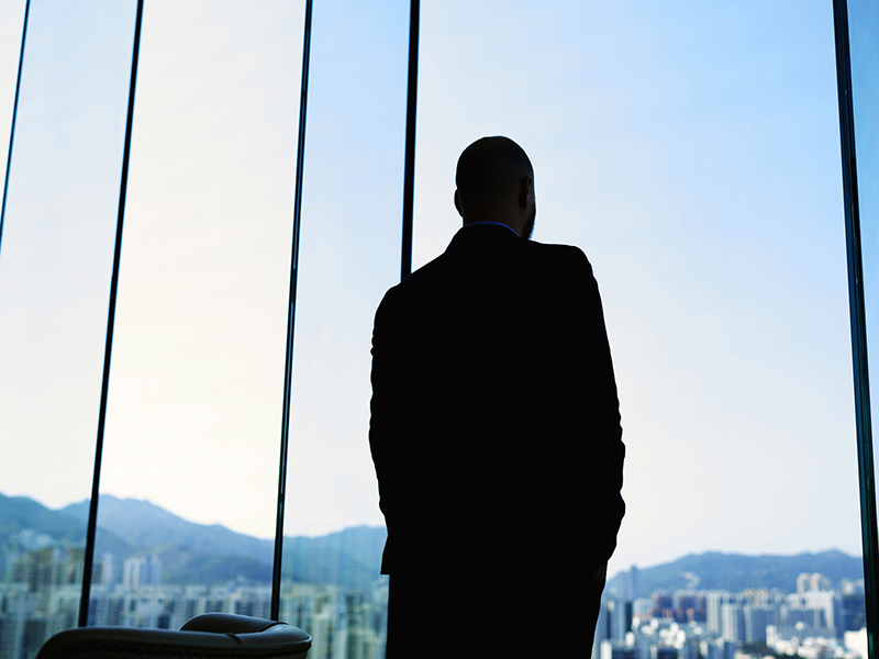 Homme d'affaires devant une fenêtre, en contre-jour.