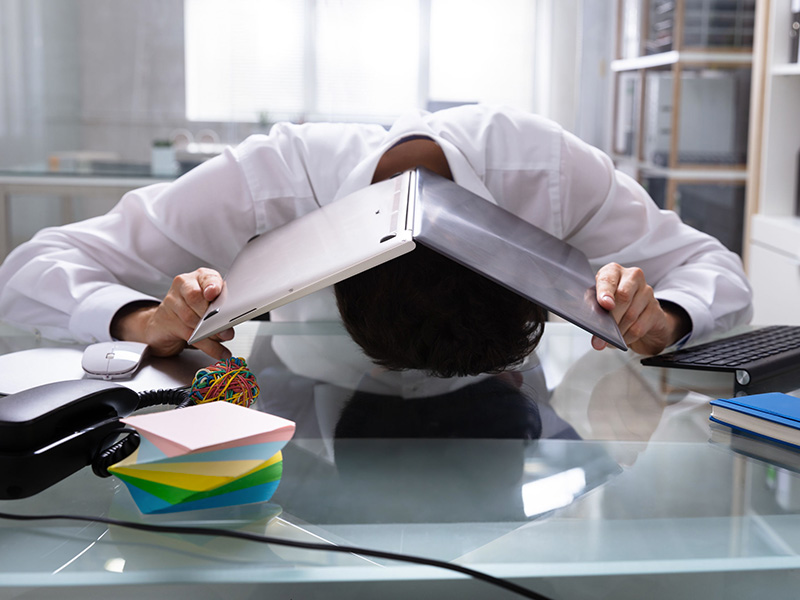 Employé se cachant sous un cartable, assis à son bureau.