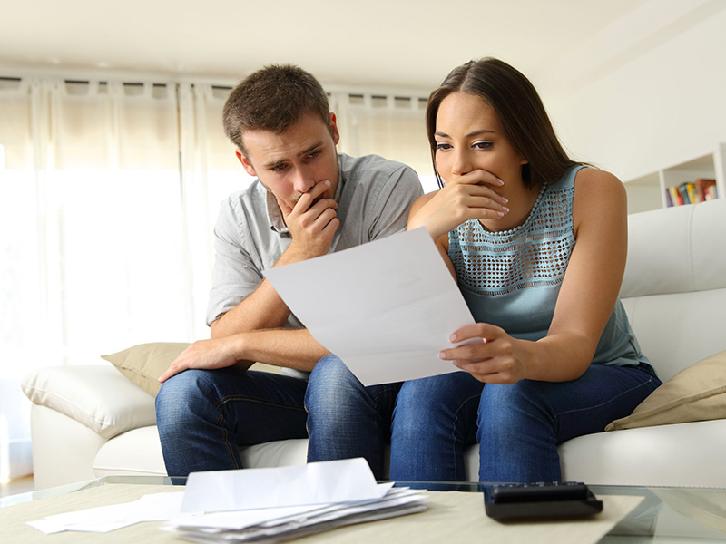 Jeune couple inquiet, examinant des documents.