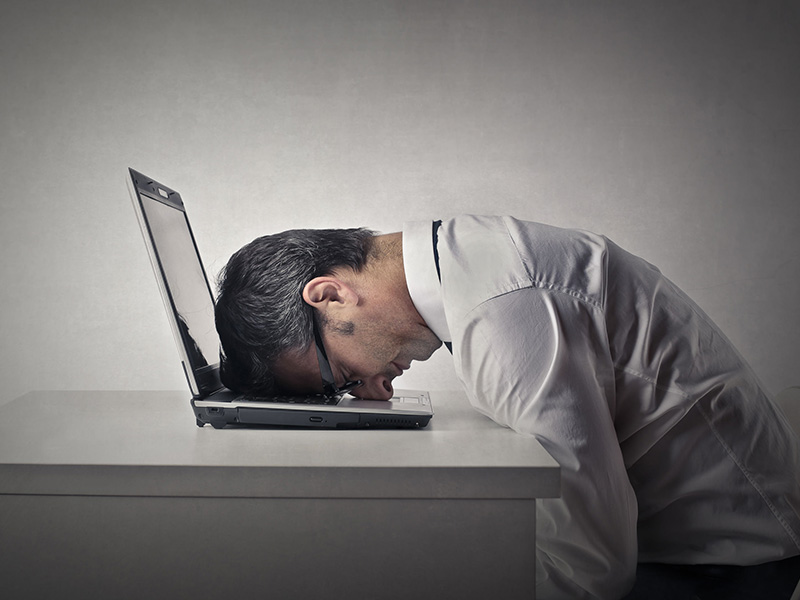 Homme la tête couchée sur le clavier de son ordinateur.