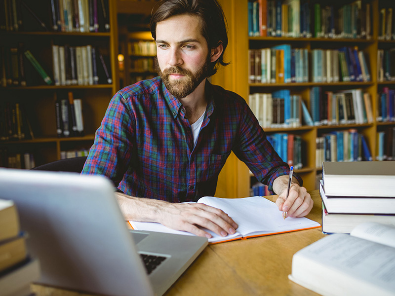 Jeune homme étudiant dans une bibliothèque.