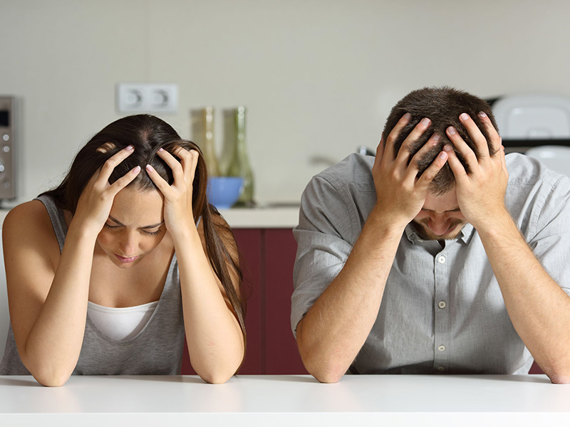 Jeune couple triste, les mains posées sur la tête.