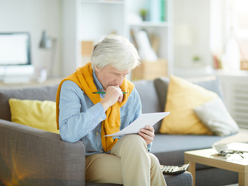 Homme retraité inquiet en consultant un document.