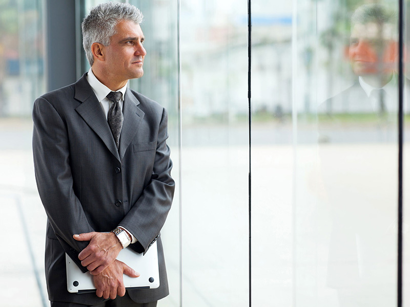 Homme d'affaires mature, regardant par la fenêtre d'un immeuble.