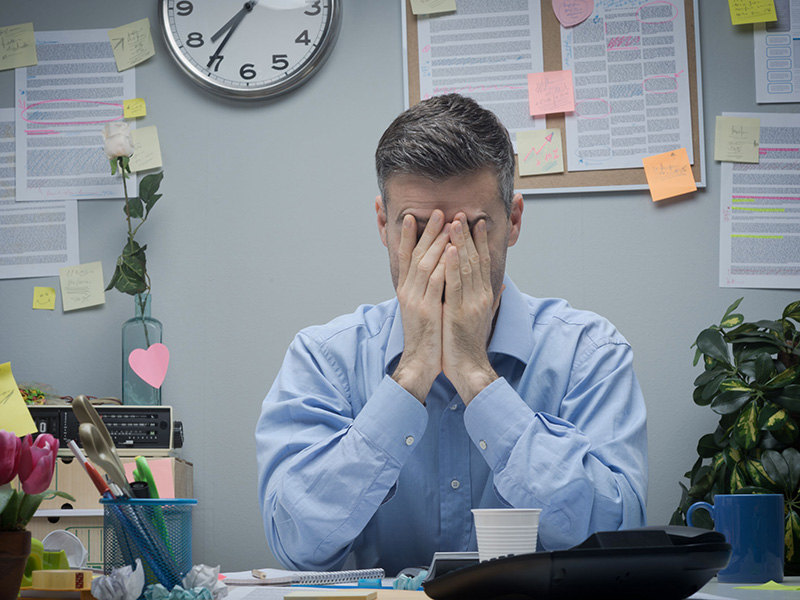 Employé de bureau se cachant le visage avec les mains.