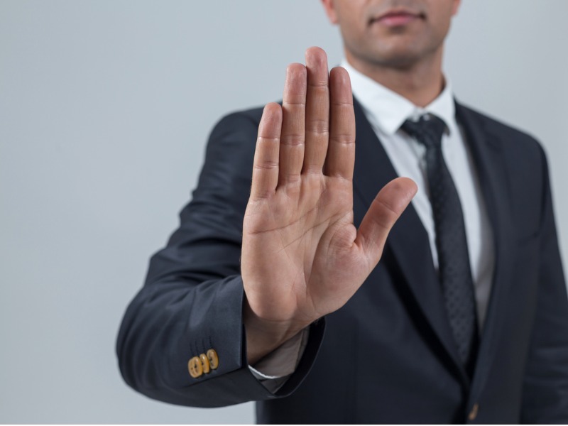 Un homme d'affaire, la main en avant, faisant le signe de stop.