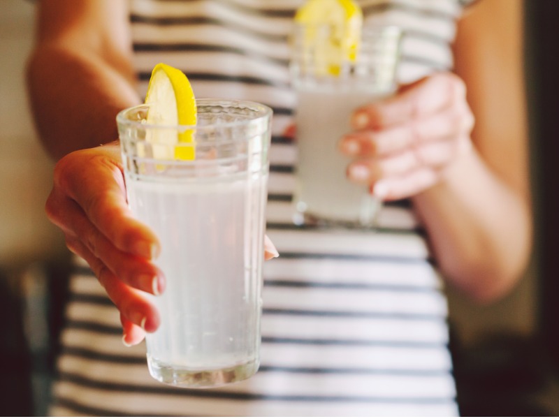 Femme qui tend un verre de limonade à quelqu'un d'autre.