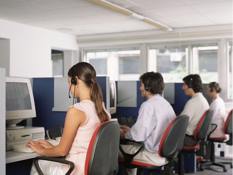 Groupe de personnes de dos faisant du télémarketing.