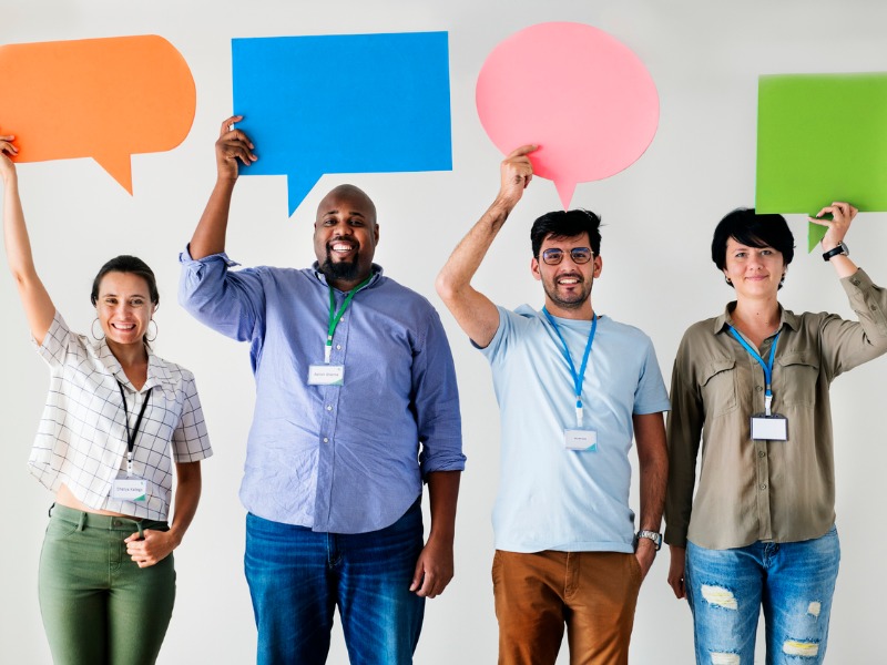 Groupe de personnes tenant des bulles de conversation de couleurs différentes.