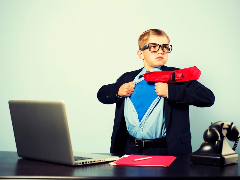 Enfant habillé en homme d'affaires qui ouvre sa chemise, révélant un costume de superhéros.