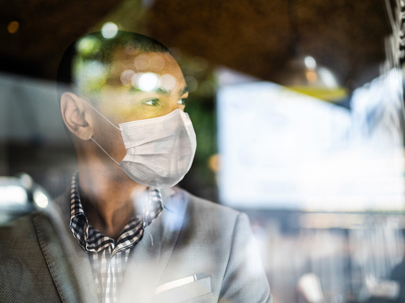 Un homme asiatique portant un masque, regarde au loin.