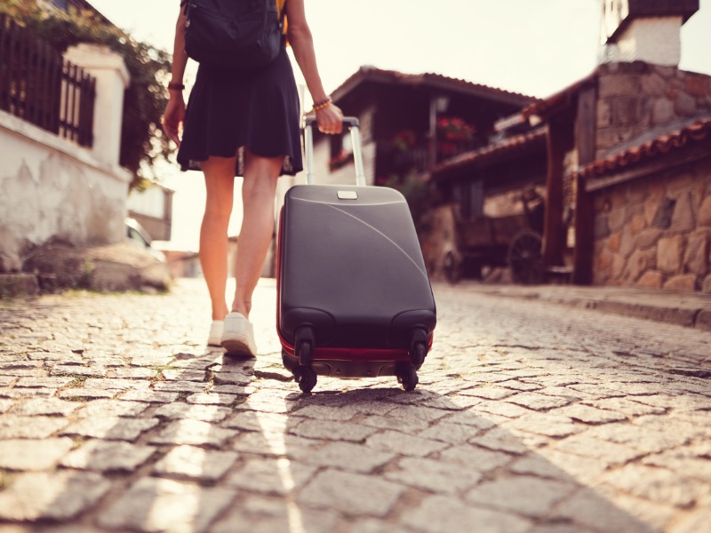 Une femme qui marche dans la rue avec une valise à la main.