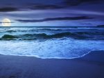 La marée sur un lever de soleil nuageux. Des vagues vertes s'écrasant sur une plage de sable doré à la lumière de la pleine lune.