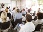 Une salle de conférence pleine d'hommes et de femmes d'affaires qui écoutent un conférencier.