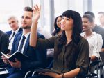 Une femme du public posant une question dans une conférence.